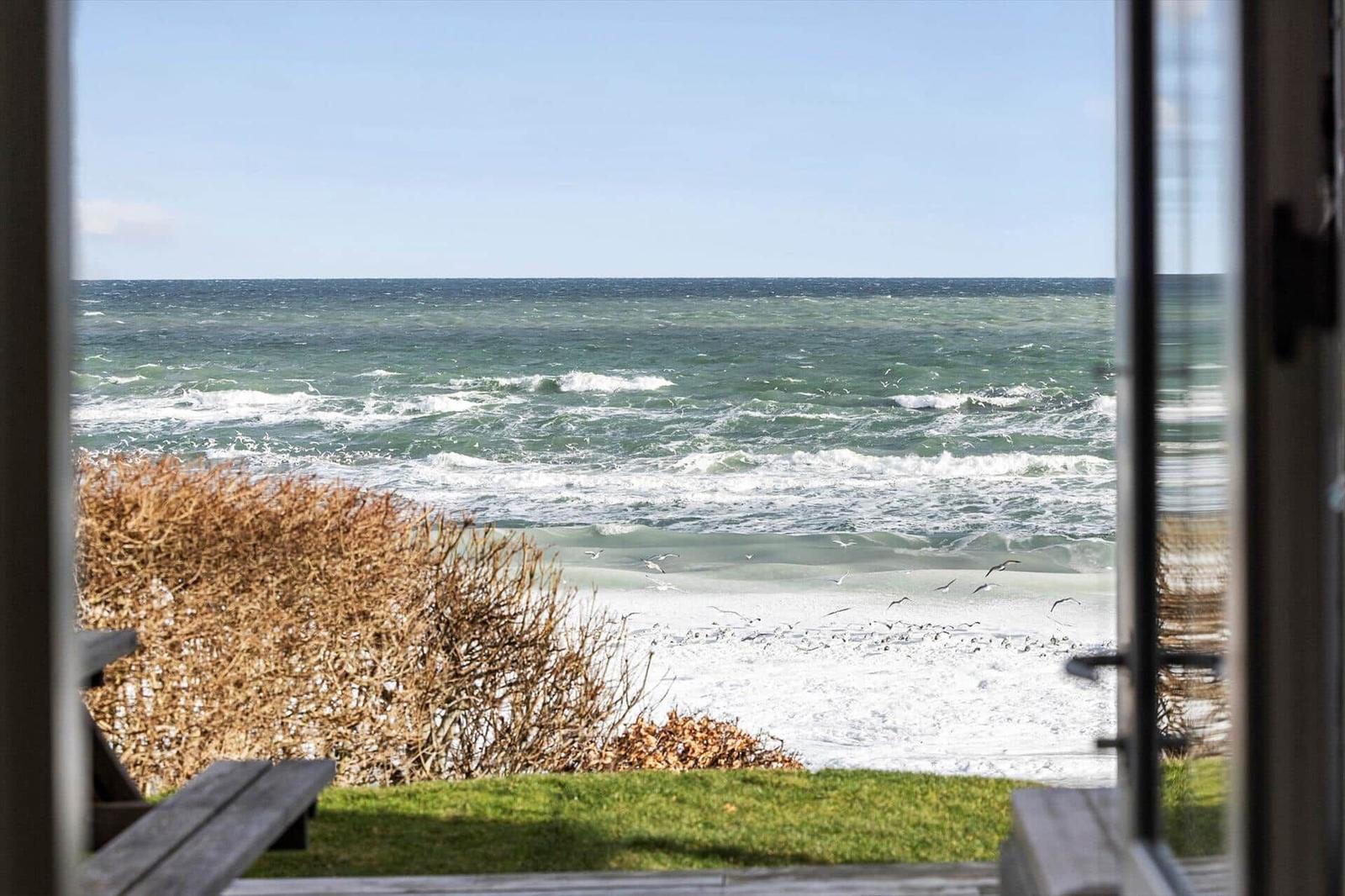 View of the sea from a window with beach and birds.