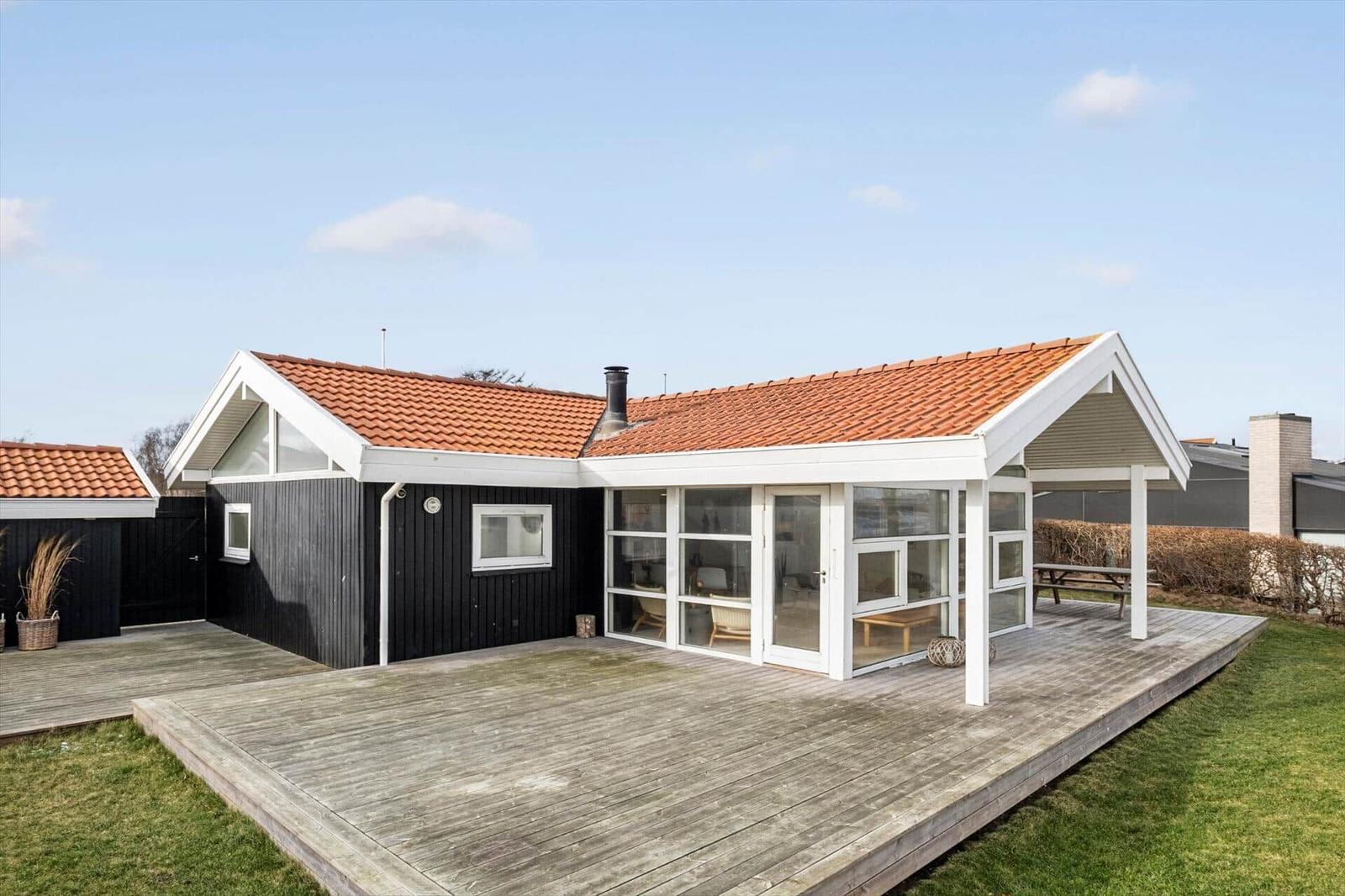 Modern villa with wooden terrace and large glass area.