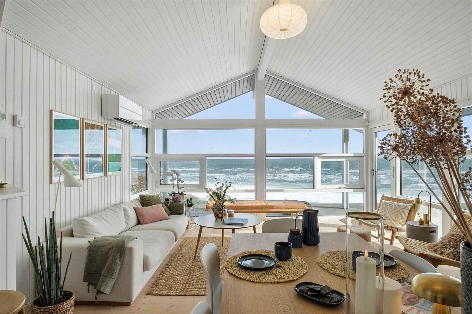 Living and dining area with ocean view through large windows.