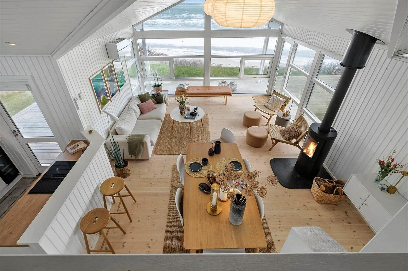 Living and dining area with fireplace and sea view through large windows.