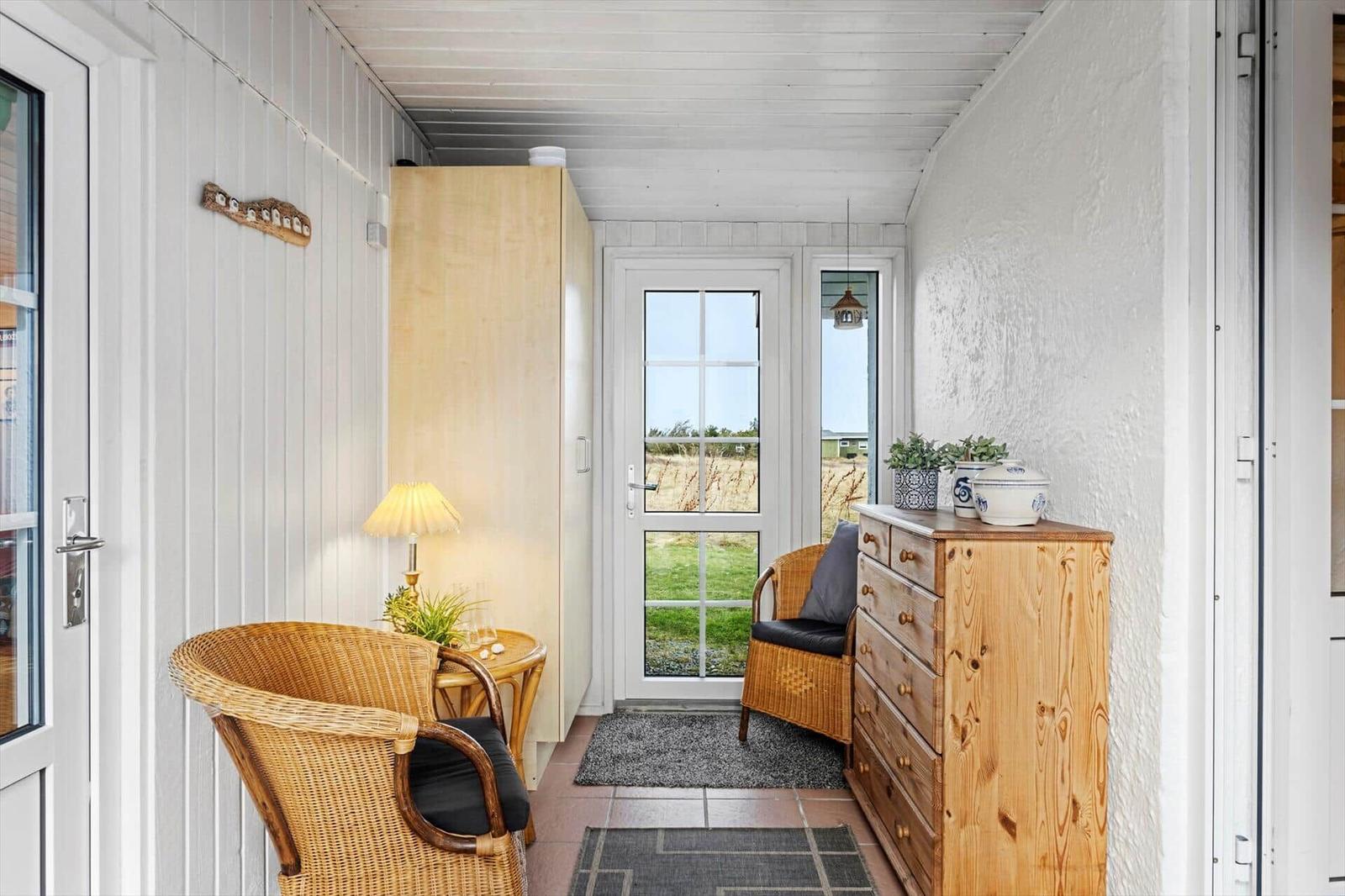Hall with wooden furniture, wicker chairs, and view of grassland.
