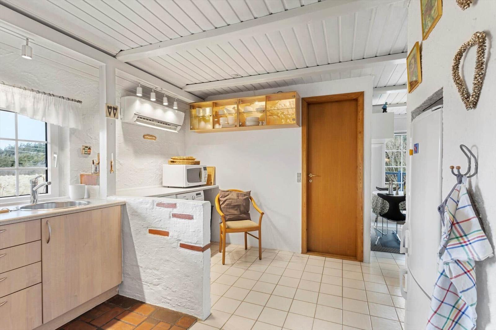 Kitchen with countertop, sink, microwave, and chair.