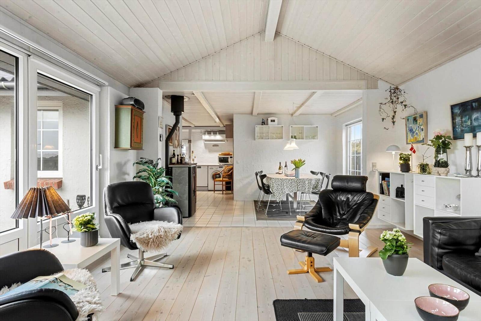 Living area with dining space, black leather chairs, and light wood floor.