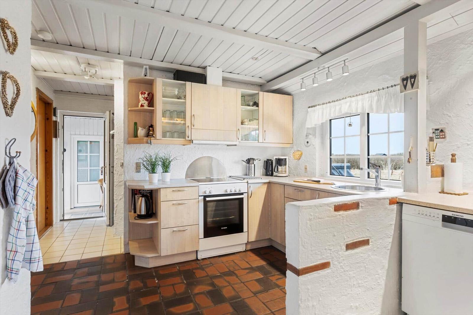 Kitchen with wooden cabinets, stove, and window with view.