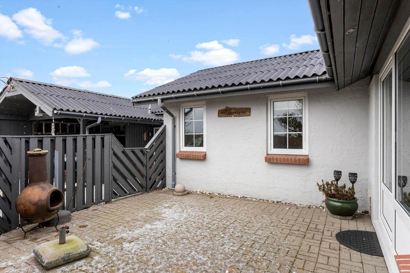 House with terrace, shed, and rustic grill. Snow covers the ground.