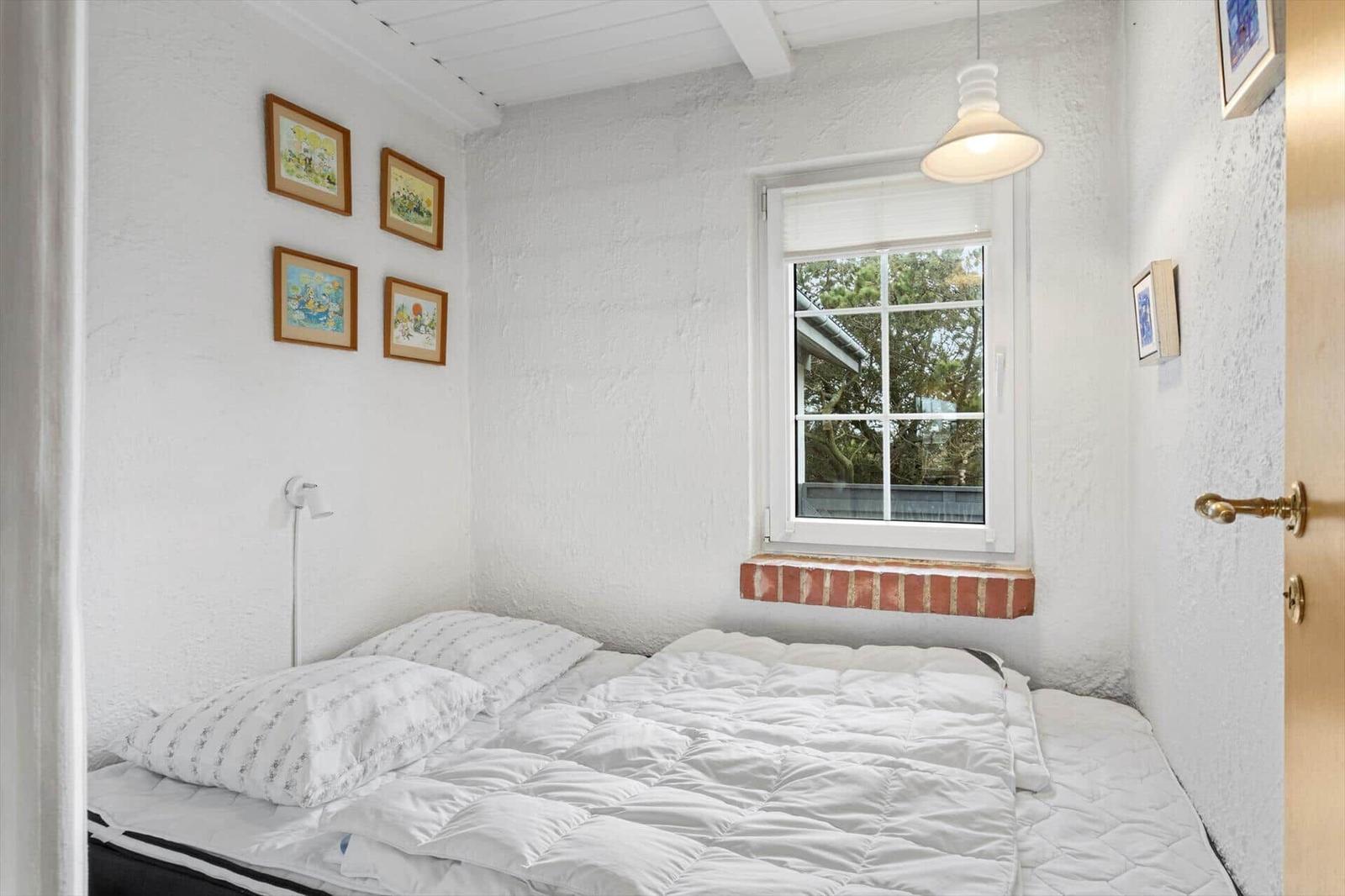 Bedroom with white walls, window, and bed.
