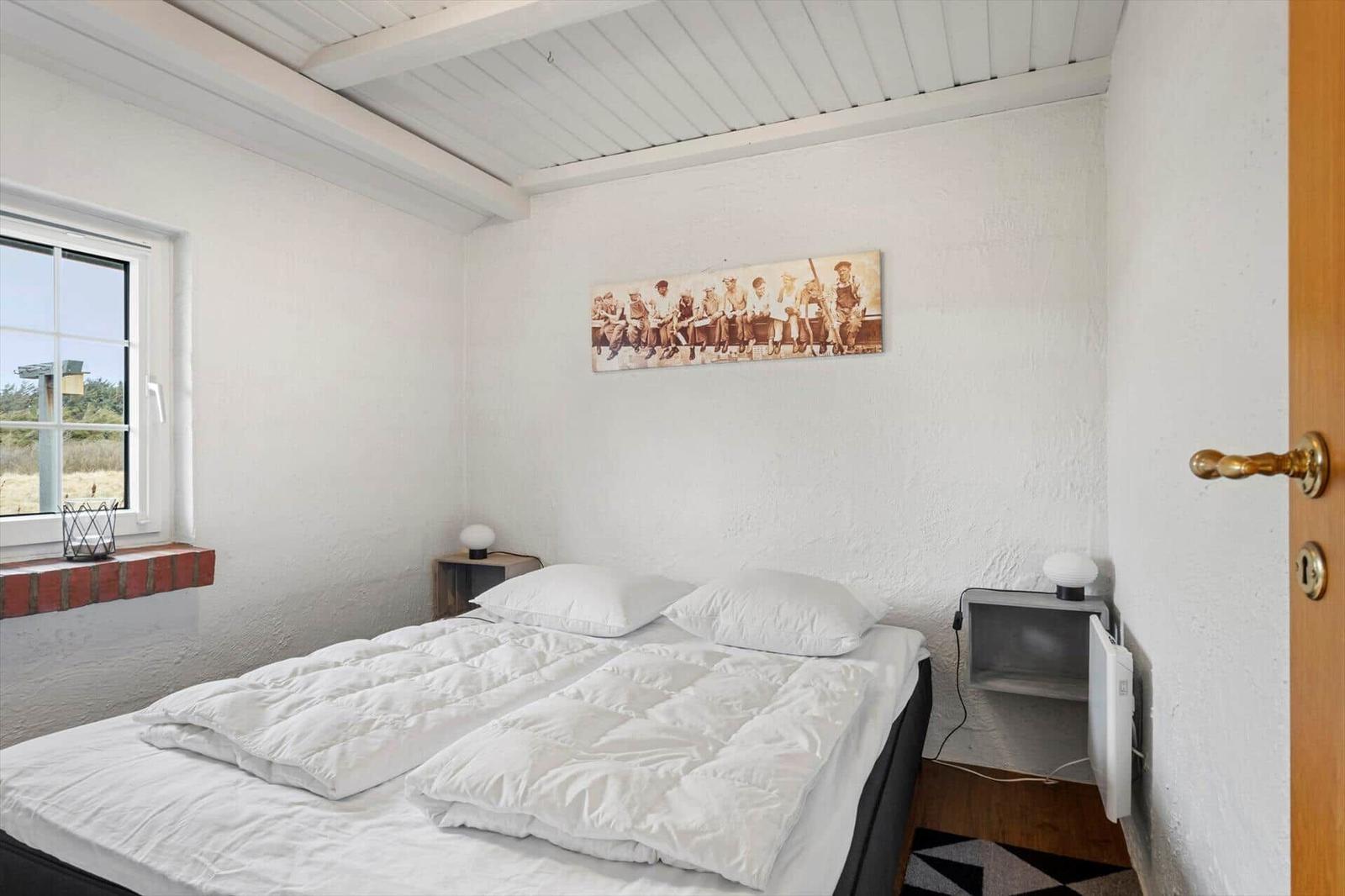 Bedroom with bed, window, and wall art.