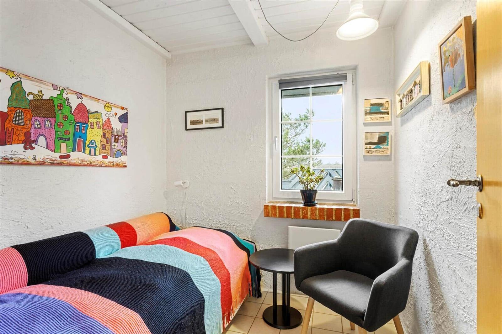 Room with bed, armchair, and window overlooking trees.