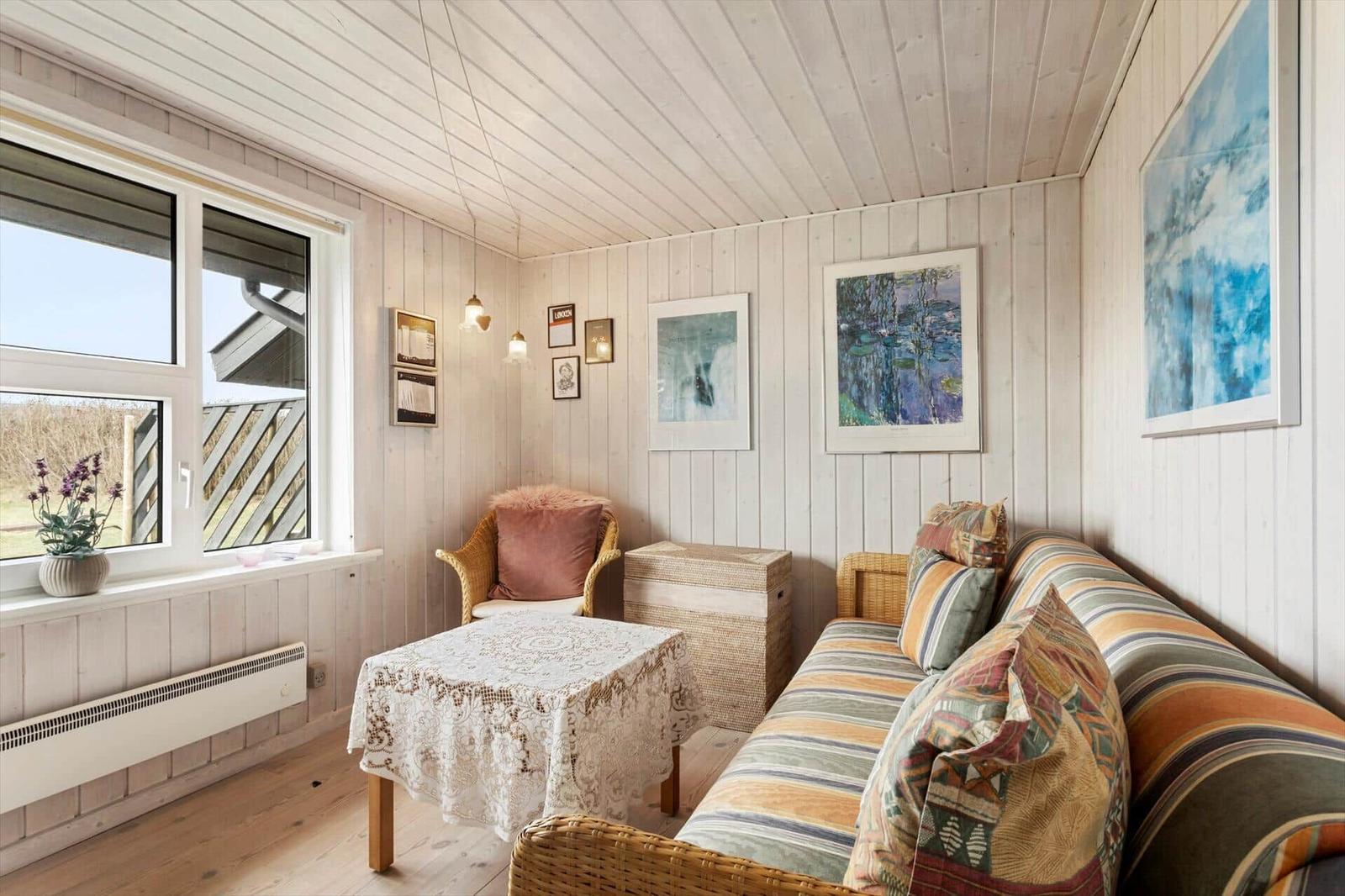 Living room with sofa, chair, and table. Wall art and window visible.