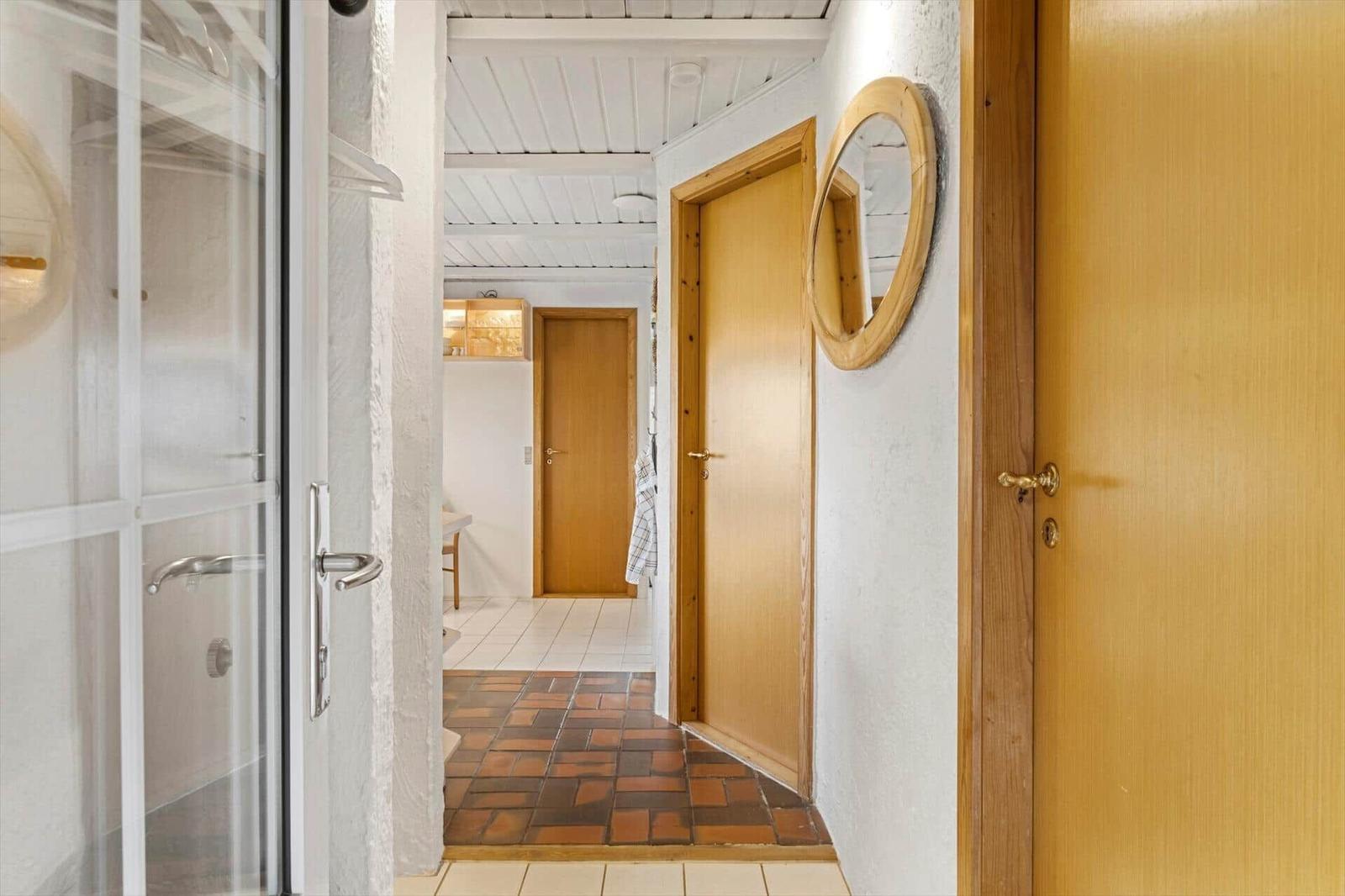 Hallway with wooden doors, round mirror, and tiled floor