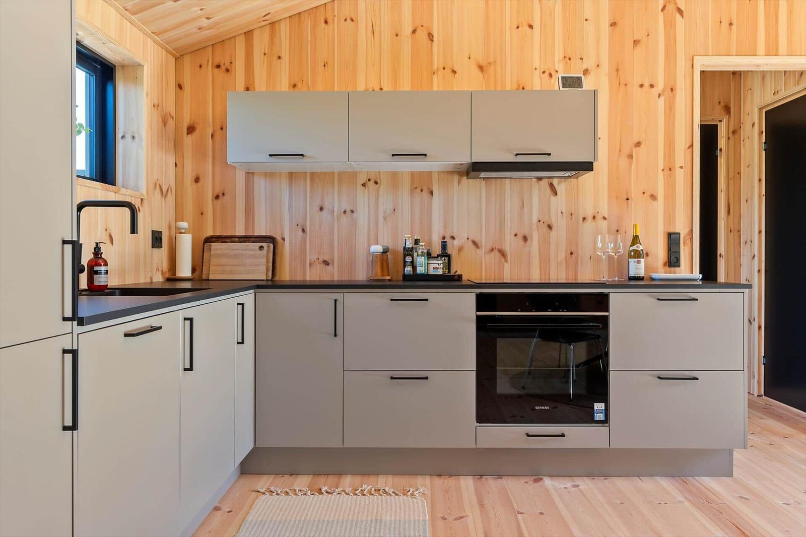 Modern kitchen with wooden walls and built-in oven.