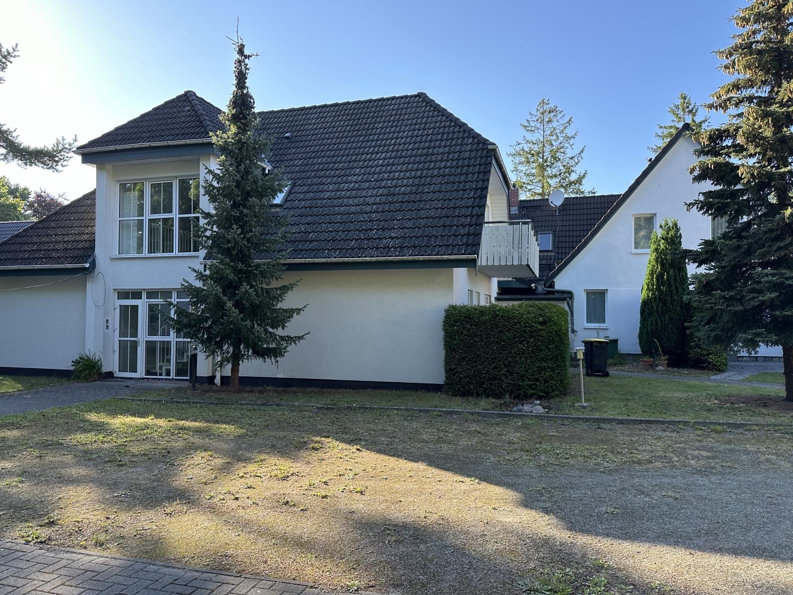 Ein weißes Haus mit dunklem Dach und Garten. 