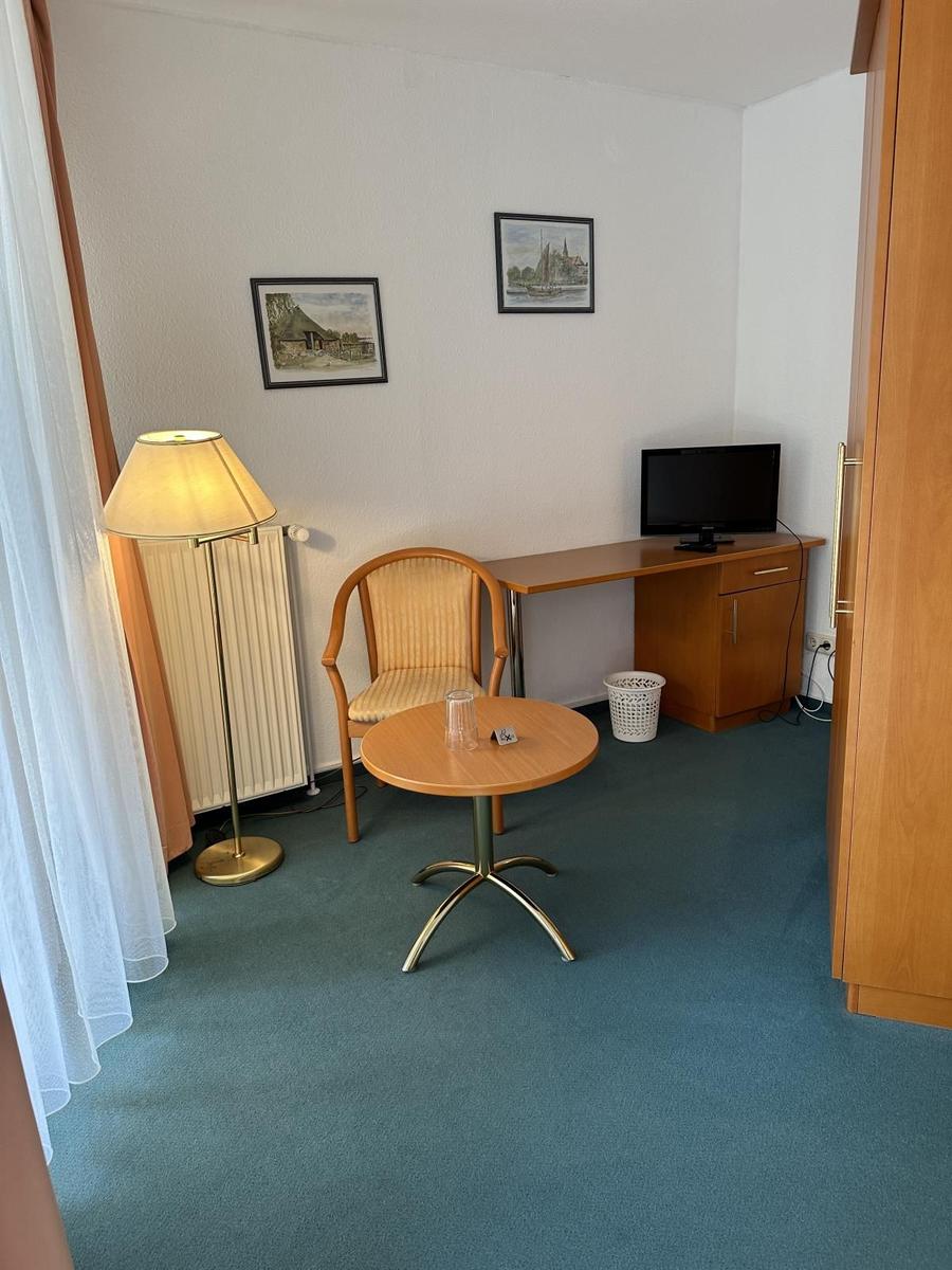 Zimmer mit Tisch, Stuhl, Schreibtisch und Fernseher.
