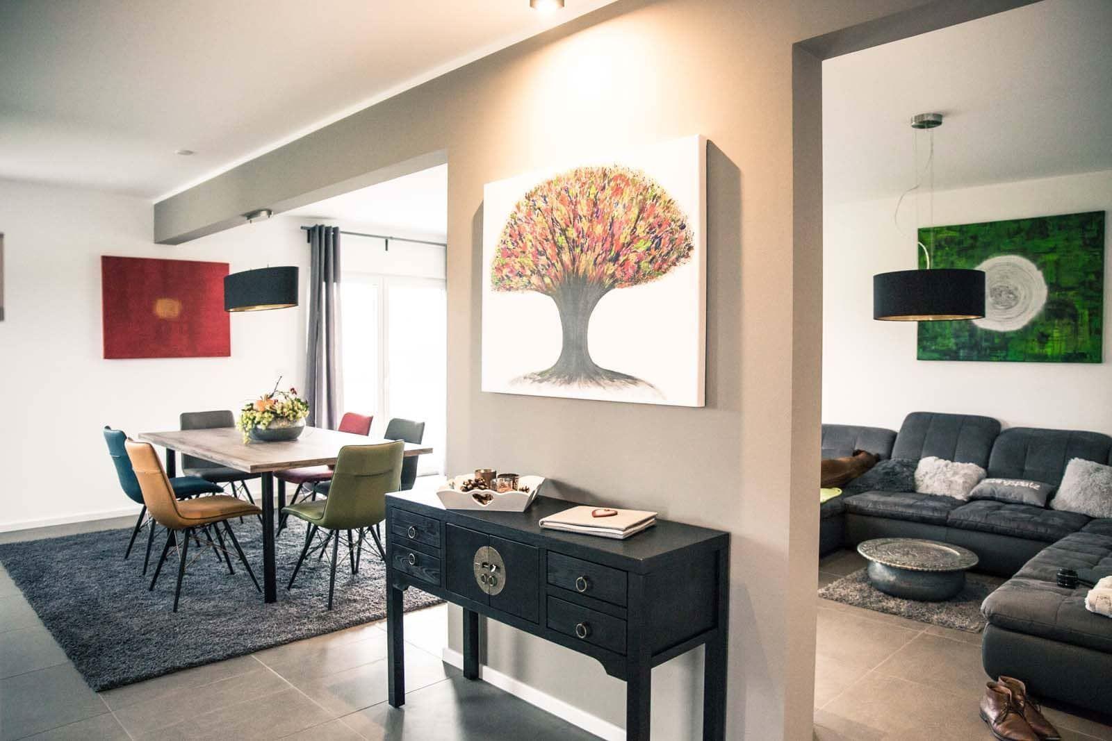 Essbereich mit Tisch und Stühlen. Wohnzimmer mit Sofa und Wandbild.