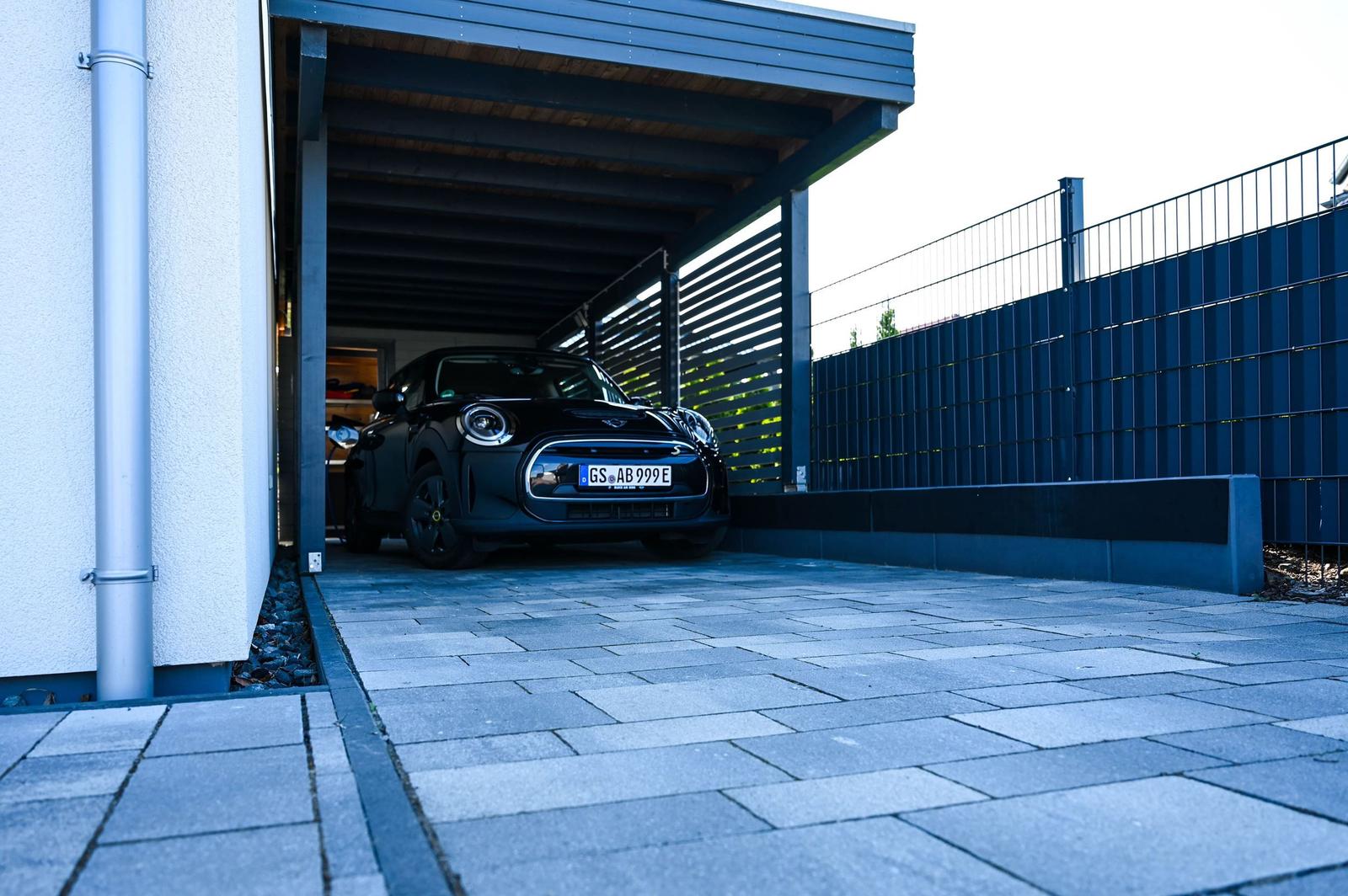 Schwarzer Mini Electric in geschützter Garage mit Pflastersteinbereich.