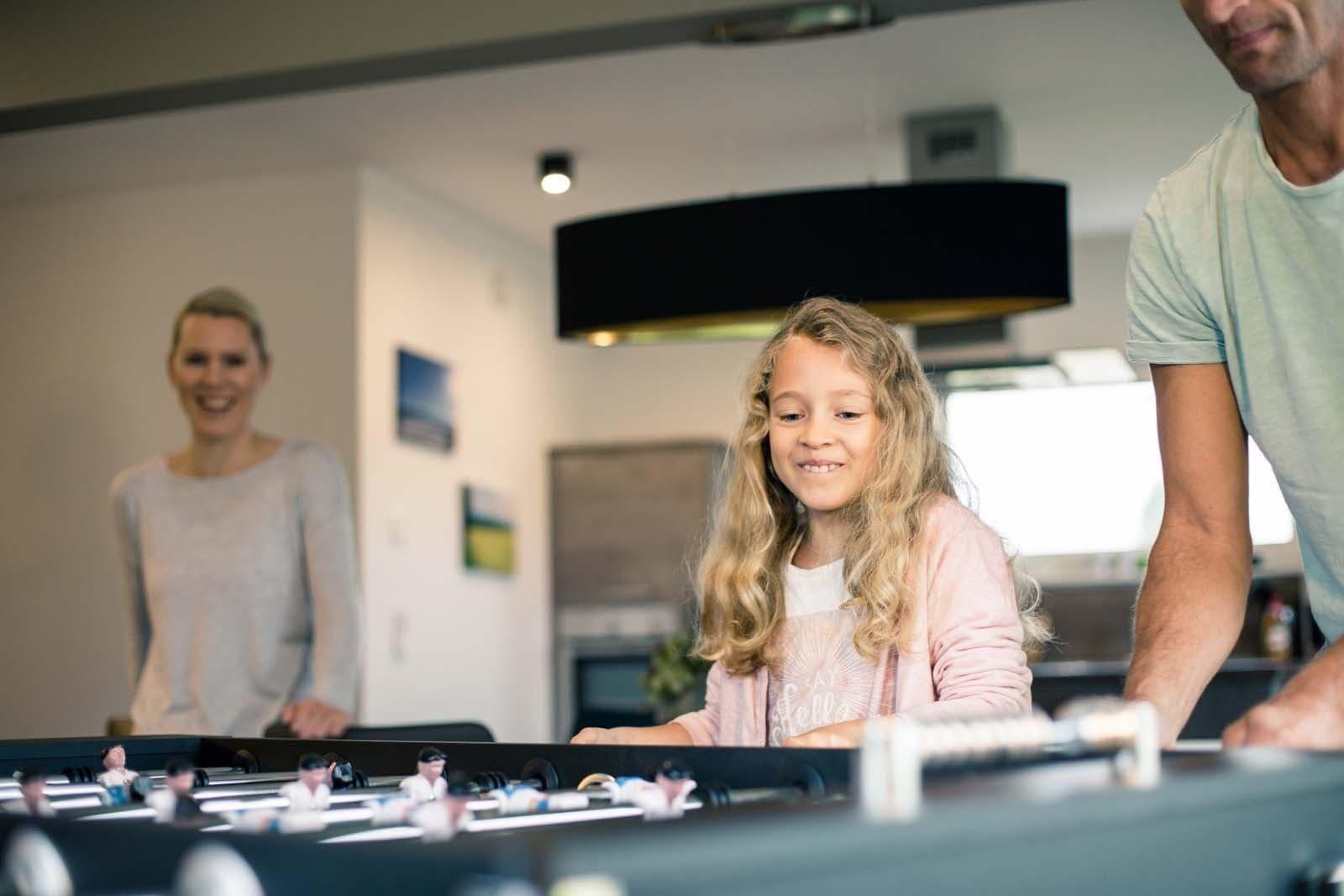 Eine Familie spielt Foosball in einer modernen Küche.