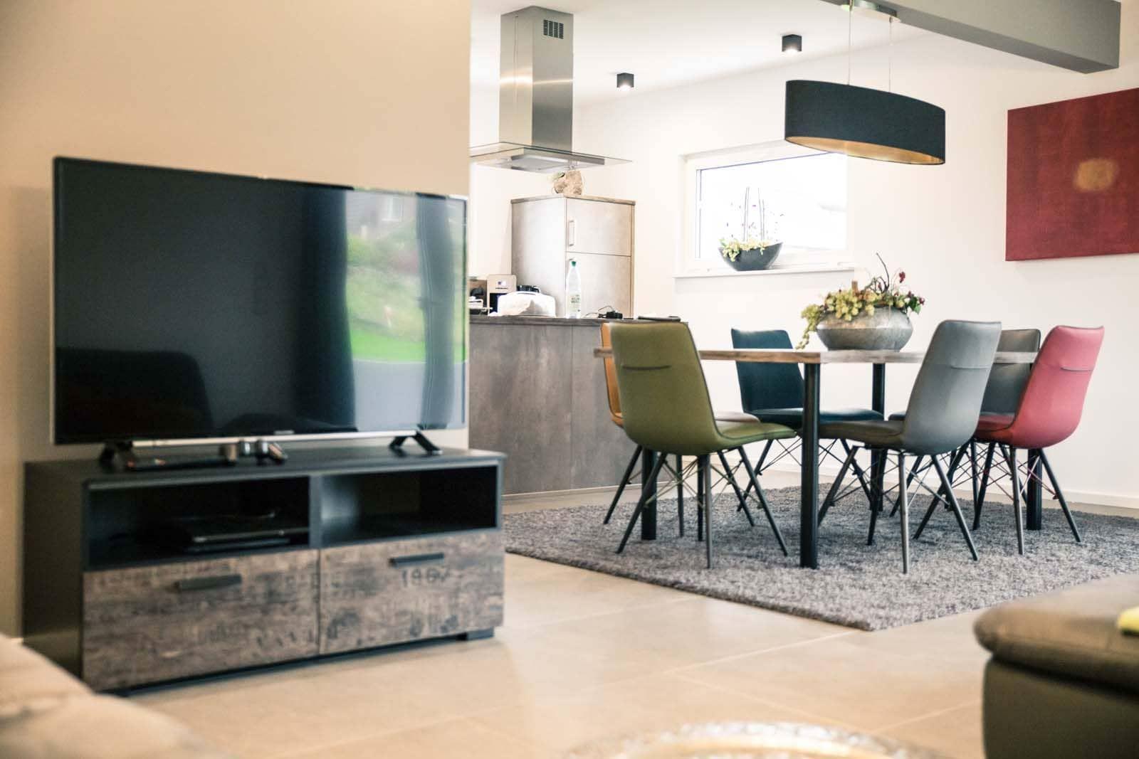 Wohn- und Essbereich mit TV, Tisch und Stühlen.