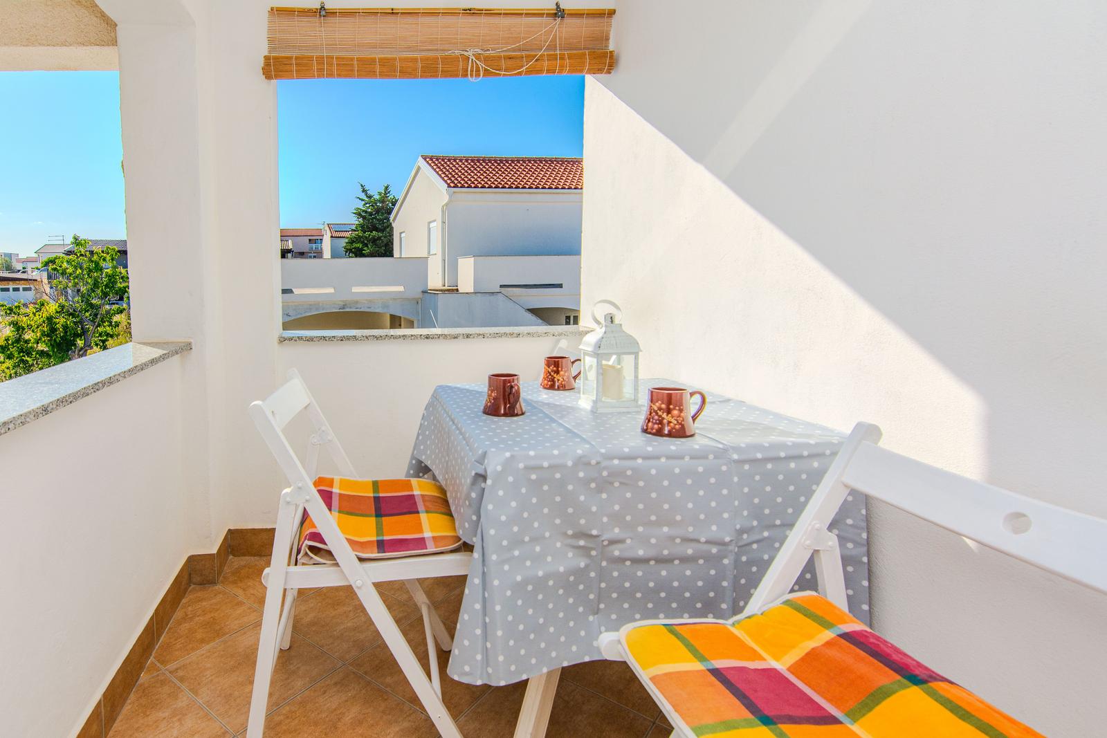 Terrasse mit Tisch, zwei Stühlen und Blick auf Haus und Baum.