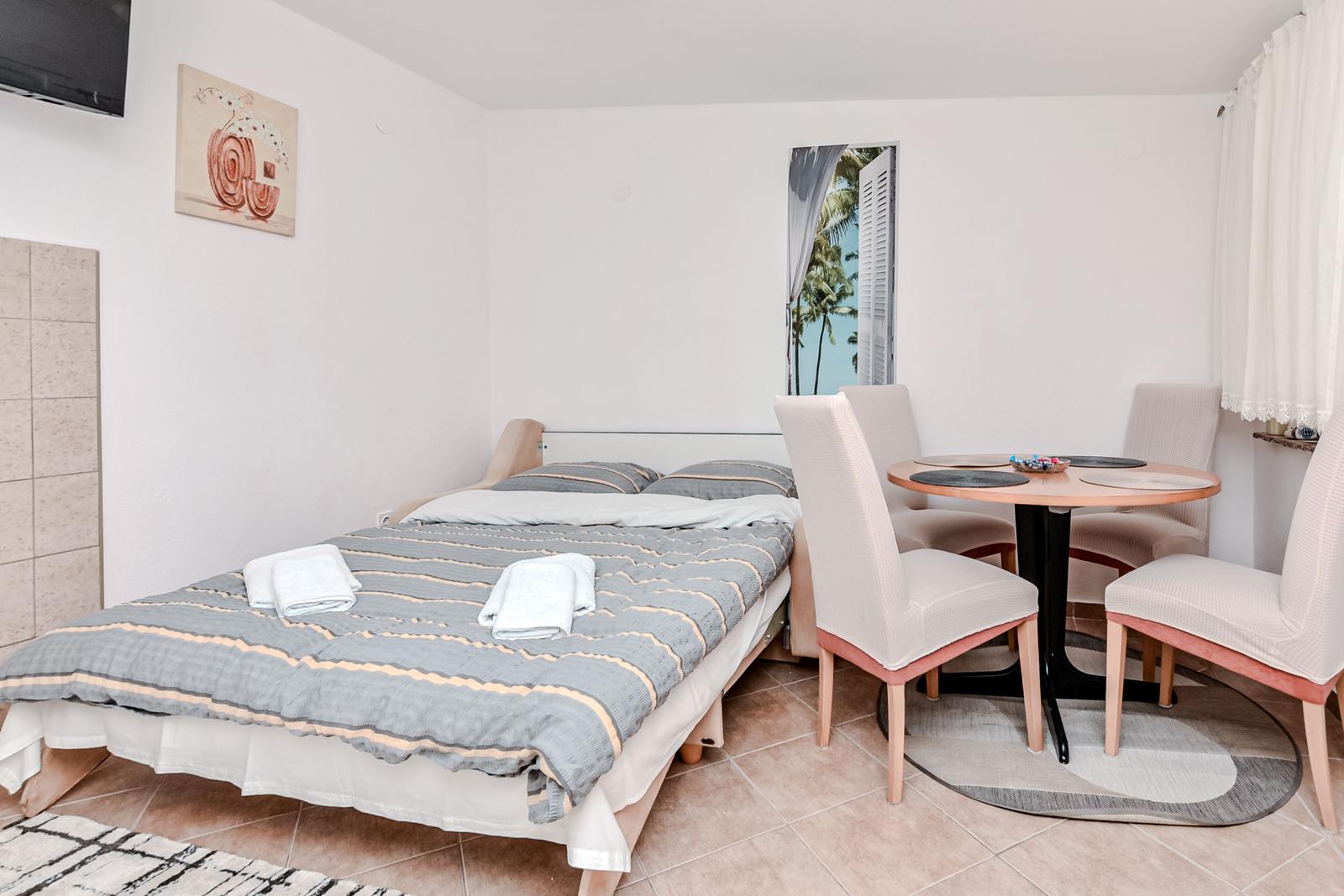 Schlafzimmer mit Bett, Esstisch und Wandbild.