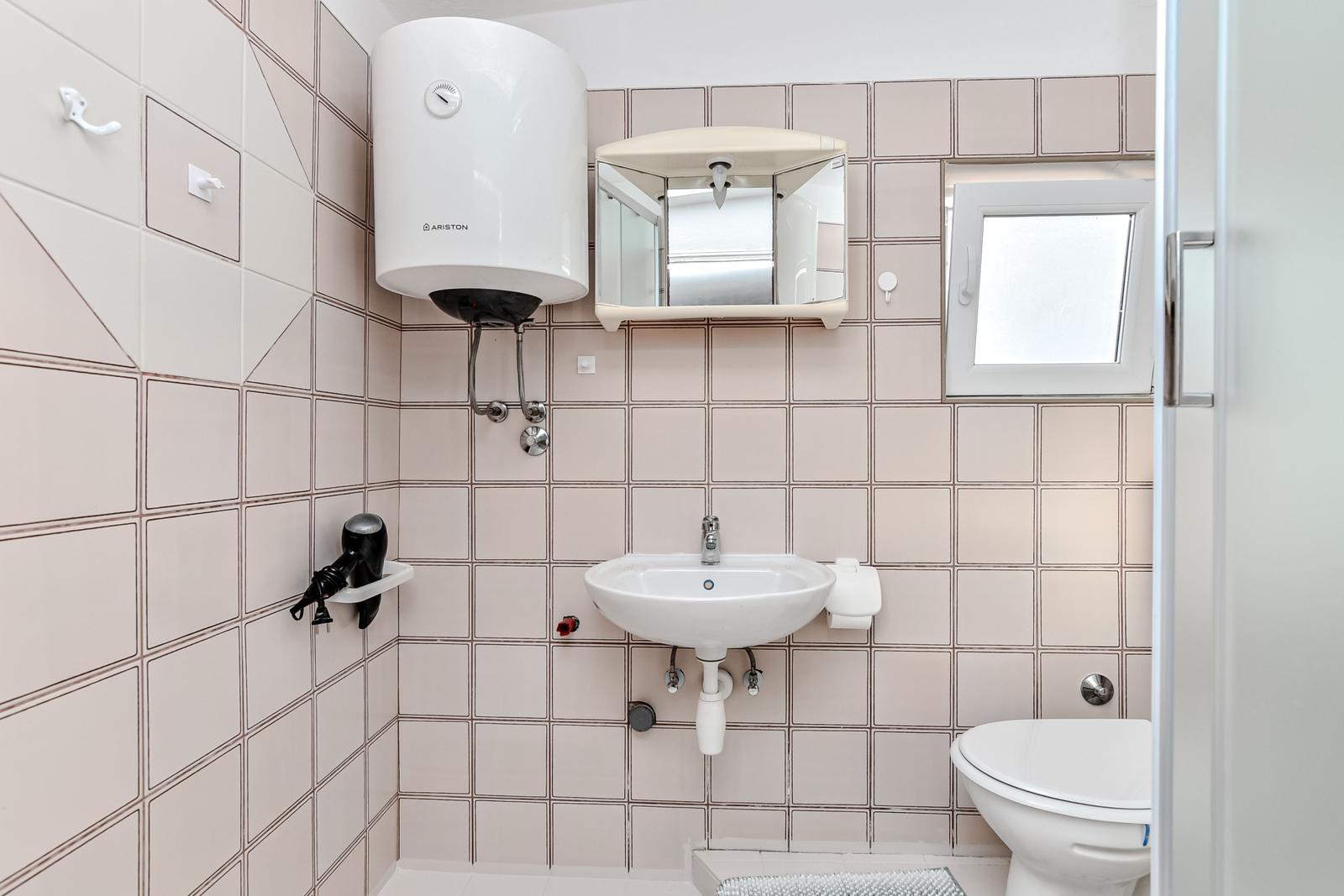 Badezimmer mit Waschbecken, Toilette und Duschbereich.