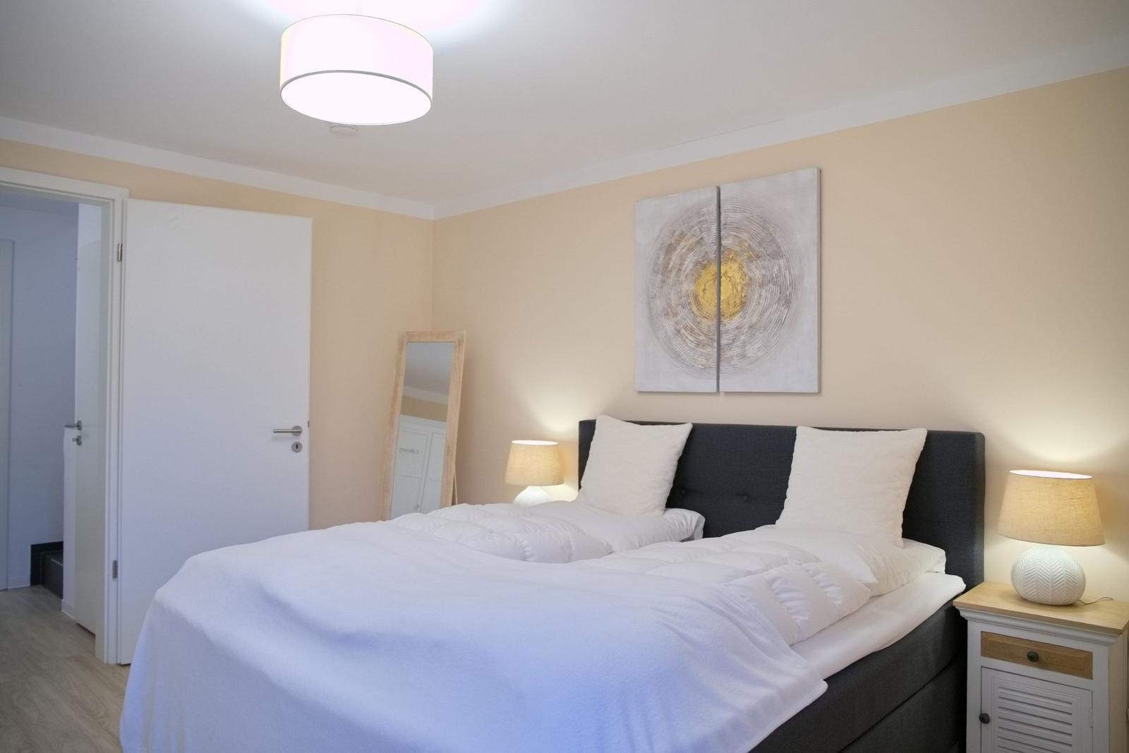 Schlafzimmer mit Bett, Nachttisch und Wandbild.