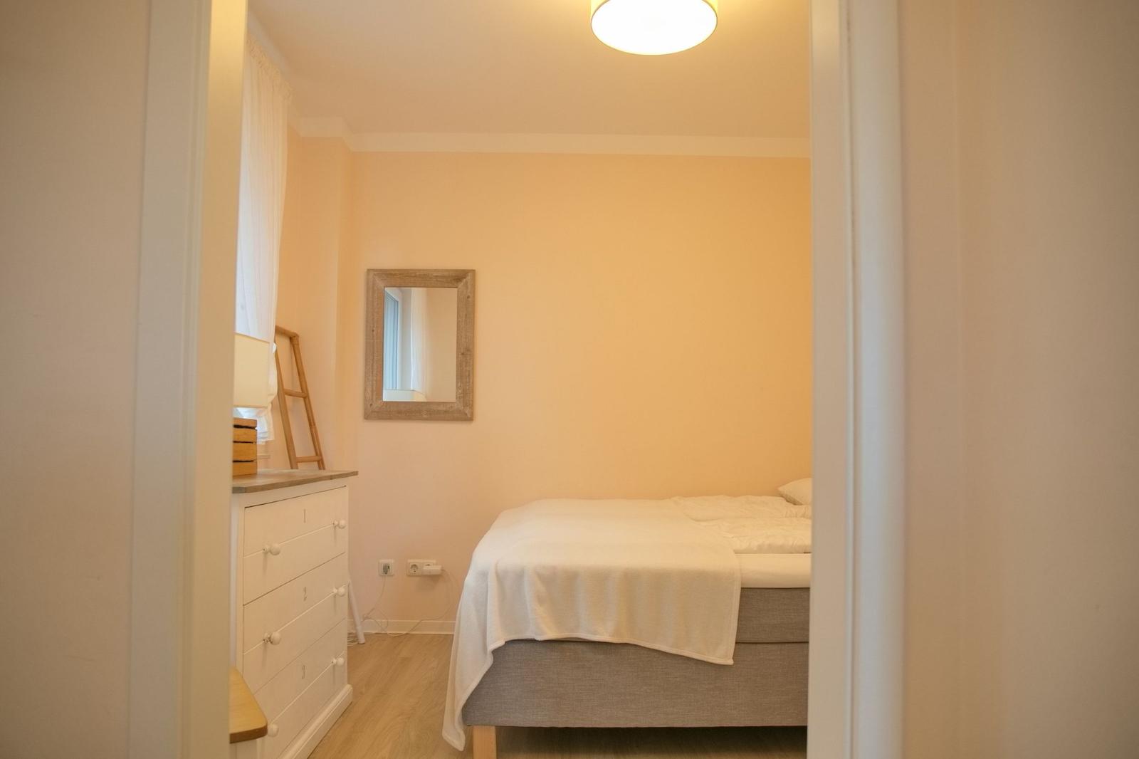 Schlafzimmer mit Bett, Kleiderschrank und Spiegel an der Wand.