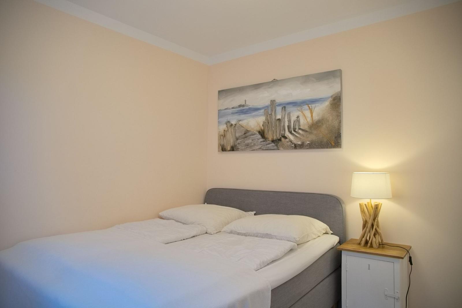 Schlafzimmer mit Bett, Nachttisch und Wandbild