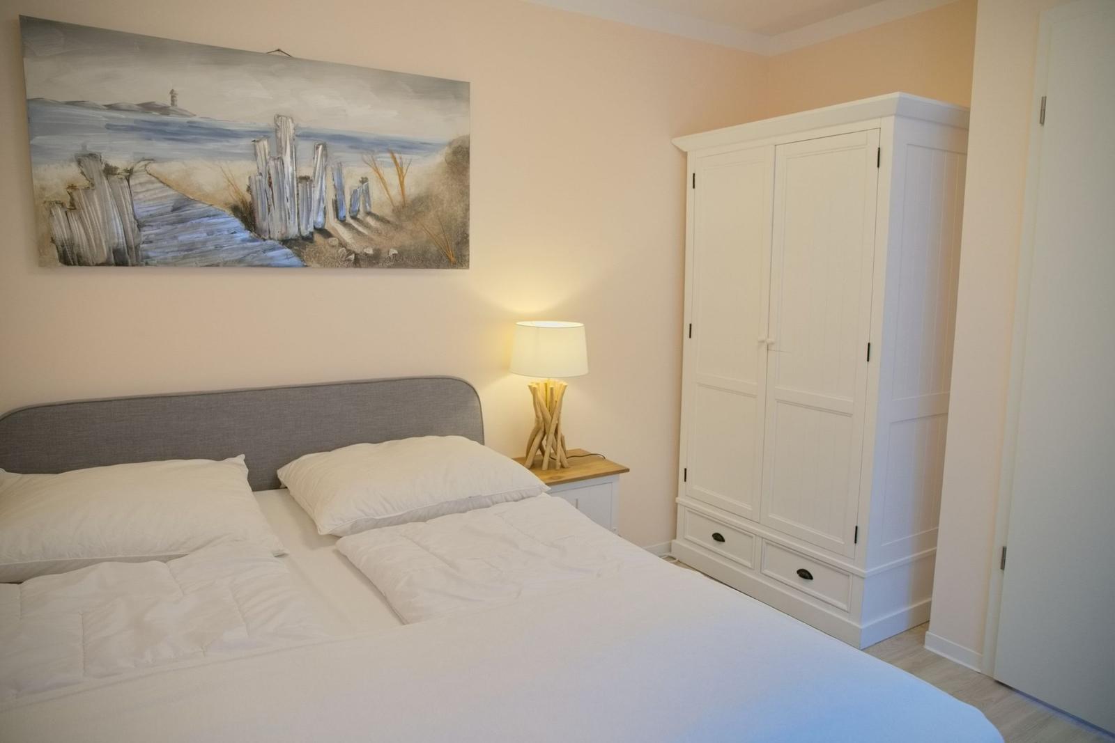Schlafzimmer mit Bett, Kleiderschrank und Wandbild.