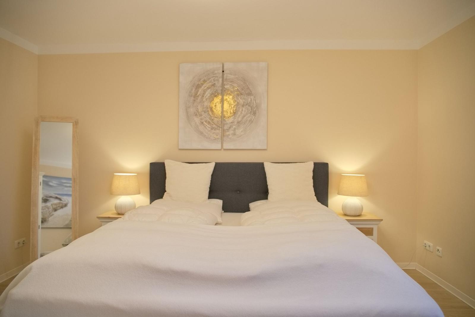 Schlafzimmer mit Doppelbett, Nachttischen und Wandbild.