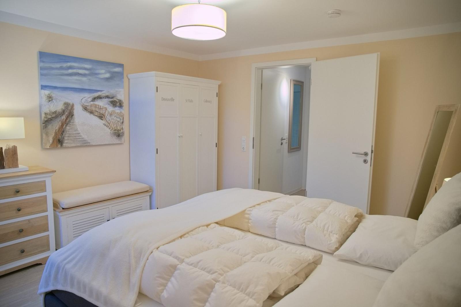 Schlafzimmer mit Bett, Kleiderschrank und Wandbild