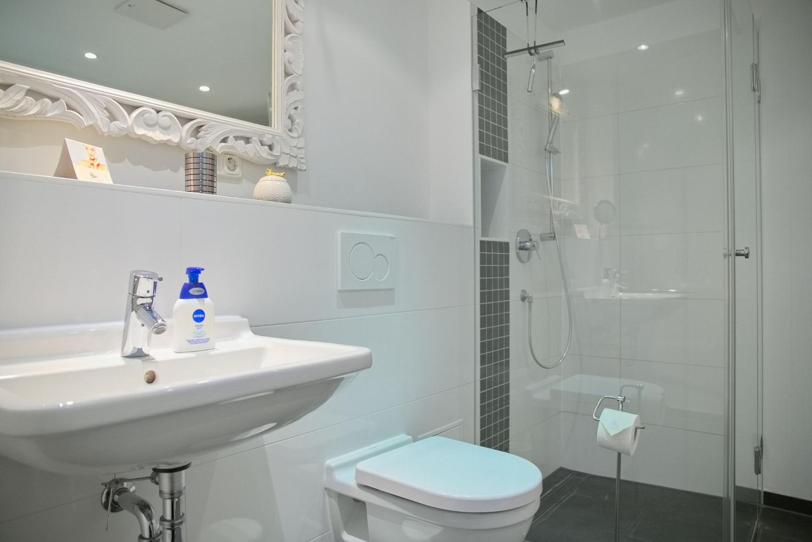 Badezimmer mit Dusche, Waschbecken und Toilette.