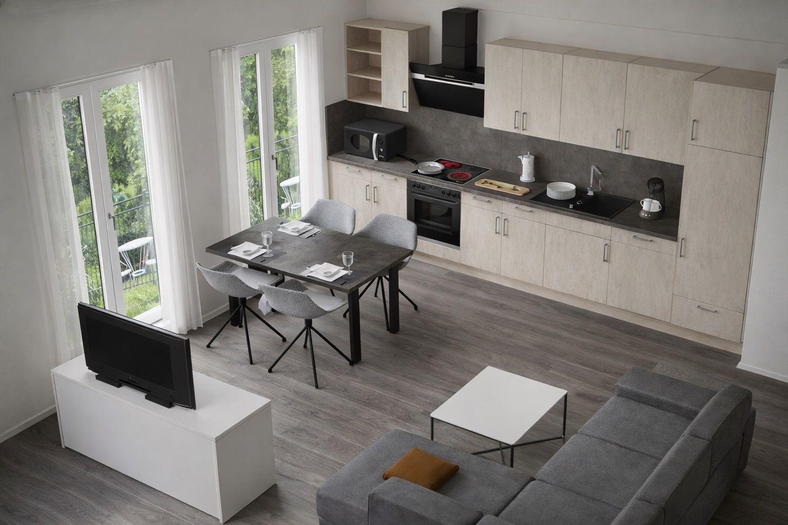 Wohnküche mit Esstisch, Sofa und TV. Durchgänge zu Balkon mit Blick auf Garten.