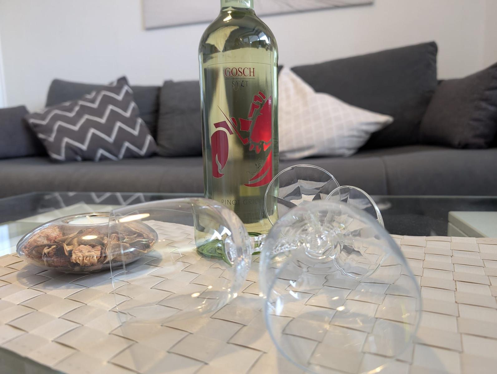 Auf dem Tisch steht eine Weißweinflasche und zwei Gläser vor einem Sofa.