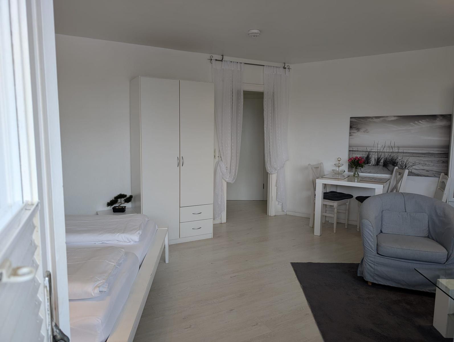 Schlafzimmer mit Bett, Kleiderschrank und Sitzbereich mit Tisch und Stühlen.