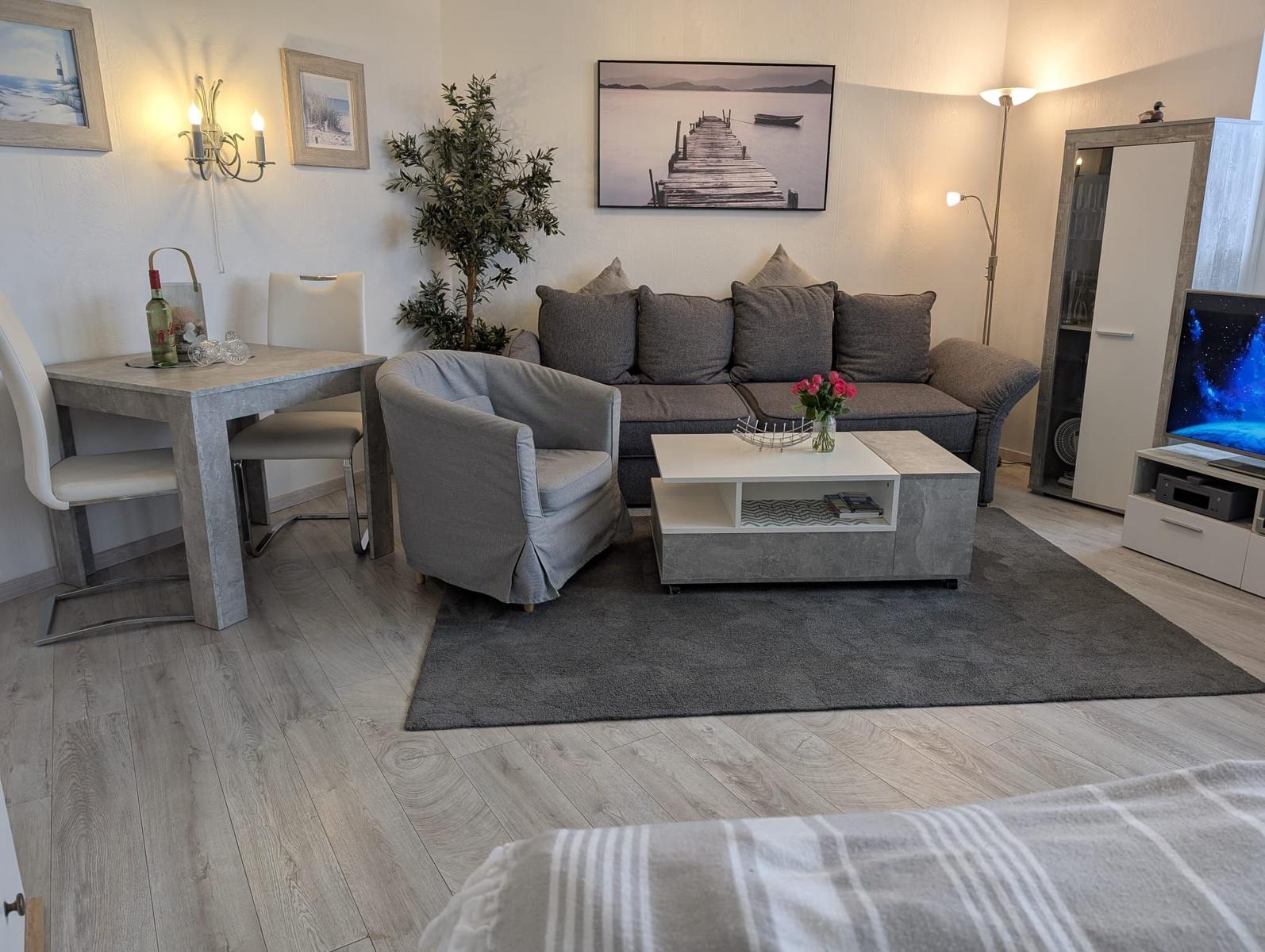 Wohnzimmer mit Sofa, Sessel, Couchtisch und Fernseher