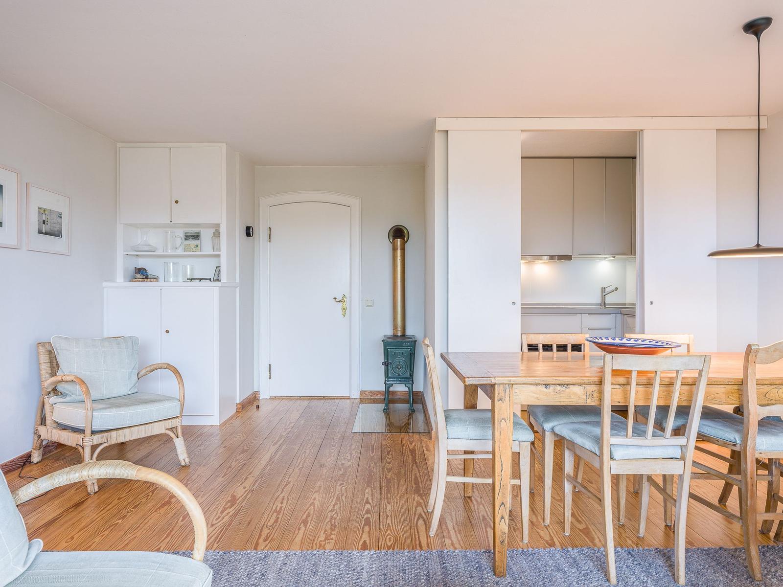 Esszimmer mit Holztisch, Stühlen und Küchenbereich im Hintergrund.