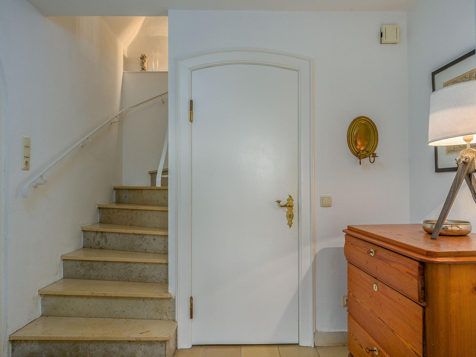 Eingangsbereich mit Treppe, Tür und Holzschrank.