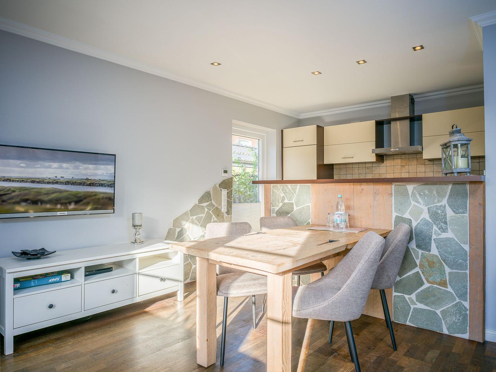 Essbereich mit Holztisch, Stühlen und Küchenzeile mit Steinwand.