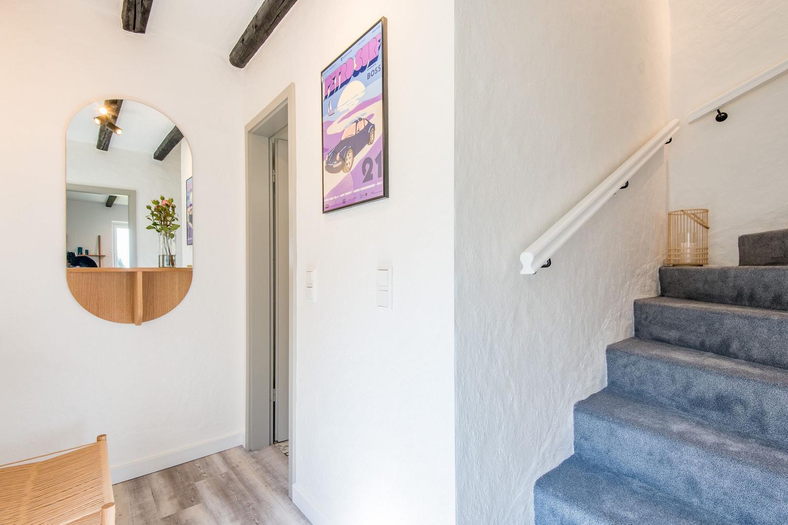 Hausgang mit Treppe, Spiegel und Wandposter.