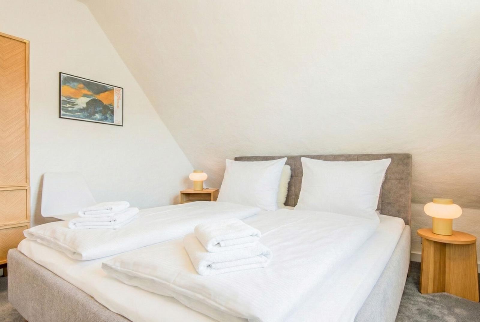 Schlafzimmer mit Doppelbett, zwei Nachttischen und einem Bild an der Wand.