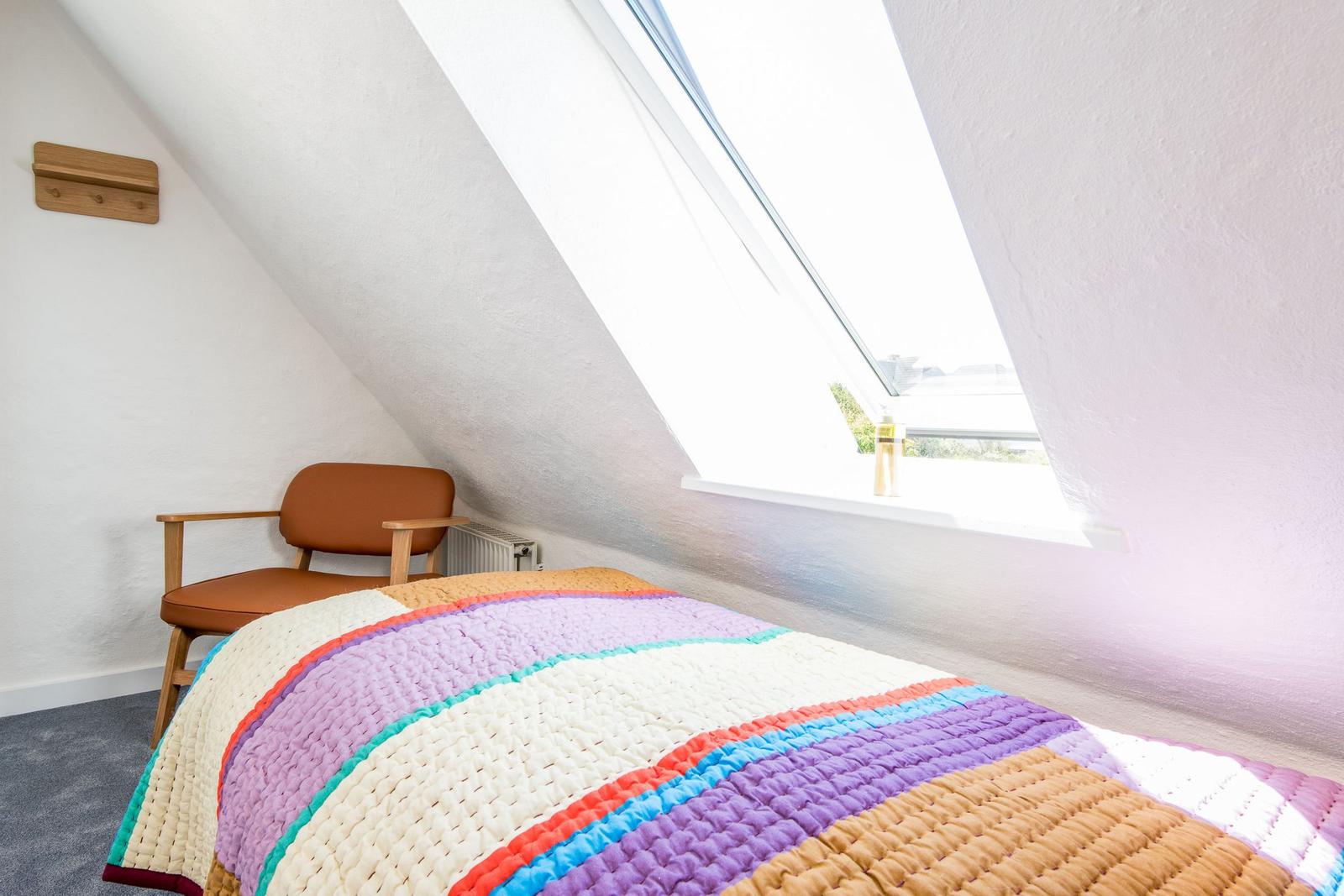 Schlafzimmer mit Dachfenster, Bett und Stuhl