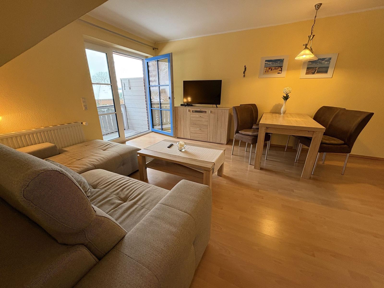 Wohn- und Essbereich mit Sofa, Esstisch und TV. Durchgang zur Terrasse.