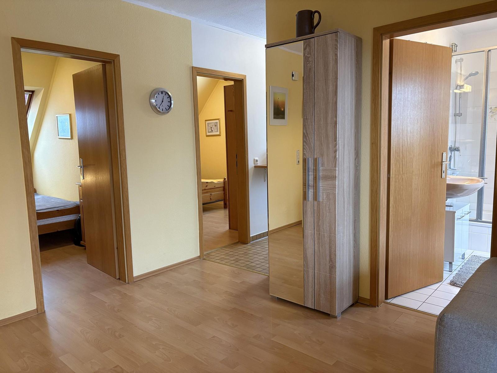 Flur mit Schlafzimmer, Bad und Kleiderschrank. Holzboden und gelbe Wände.