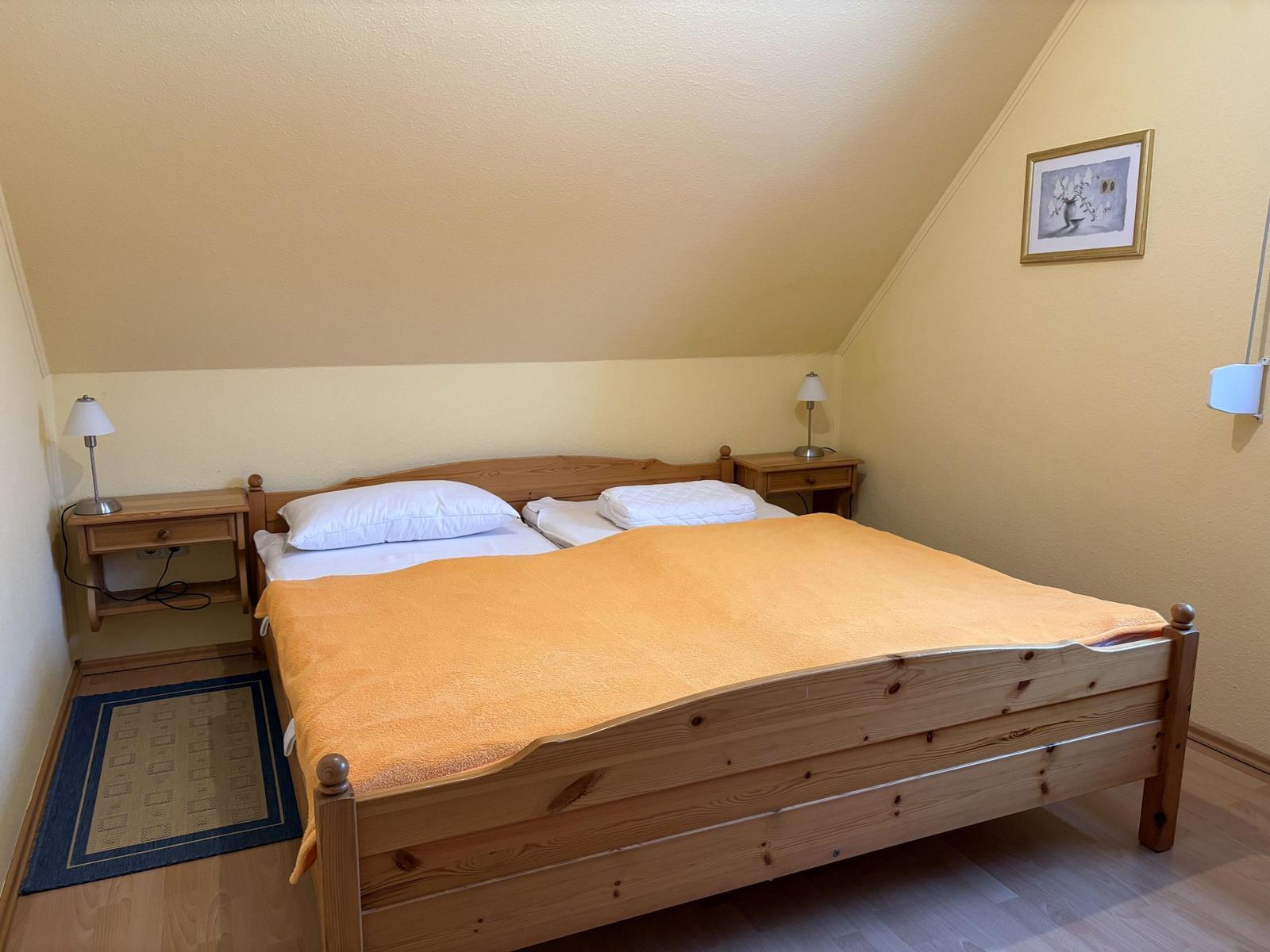 Schlafzimmer mit Holzbett, zwei Nachttischen und Lampen.