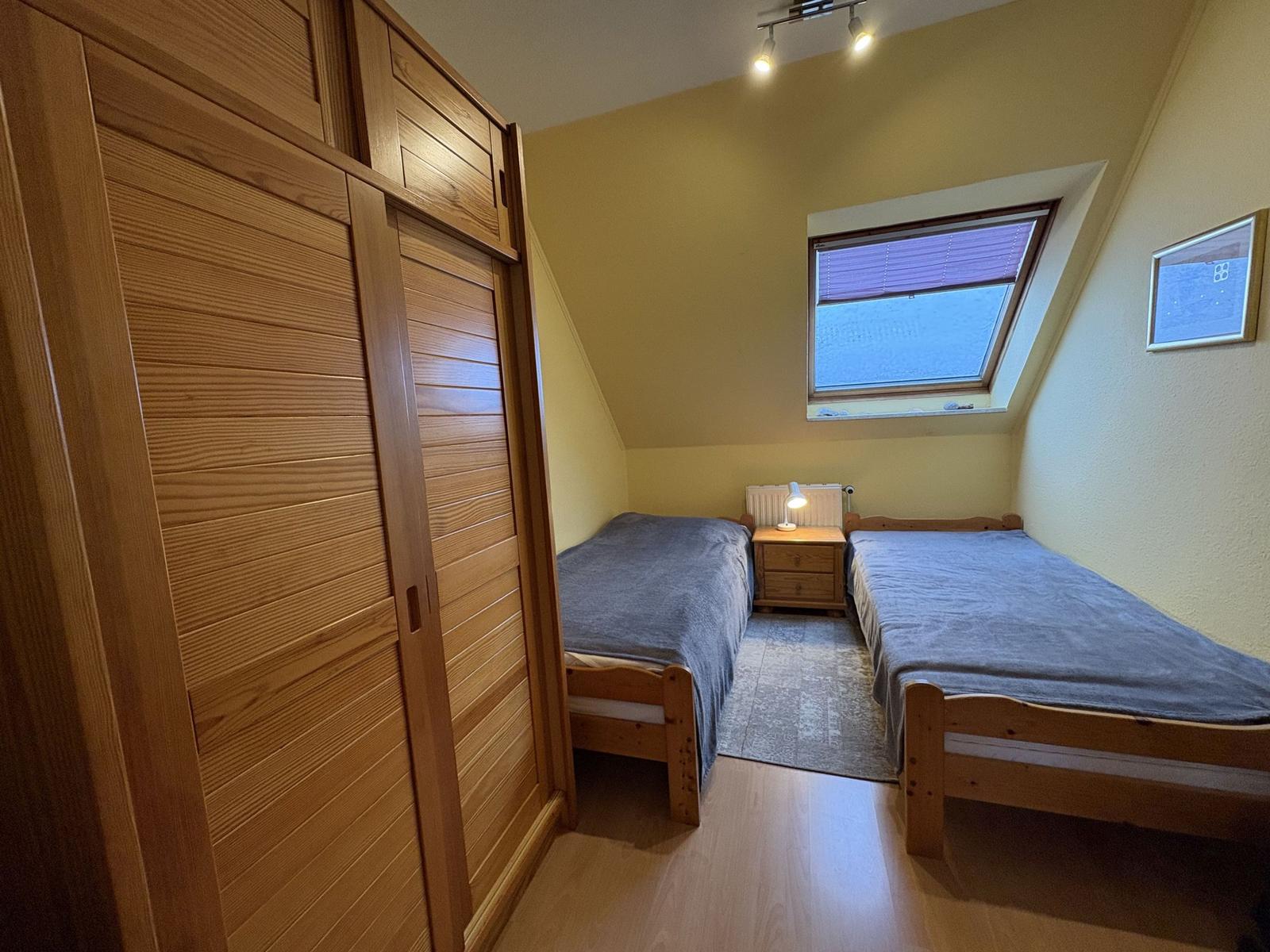 Zwei Einzelbetten, Kleiderschrank, Dachfenster und Nachttisch im Schlafzimmer.