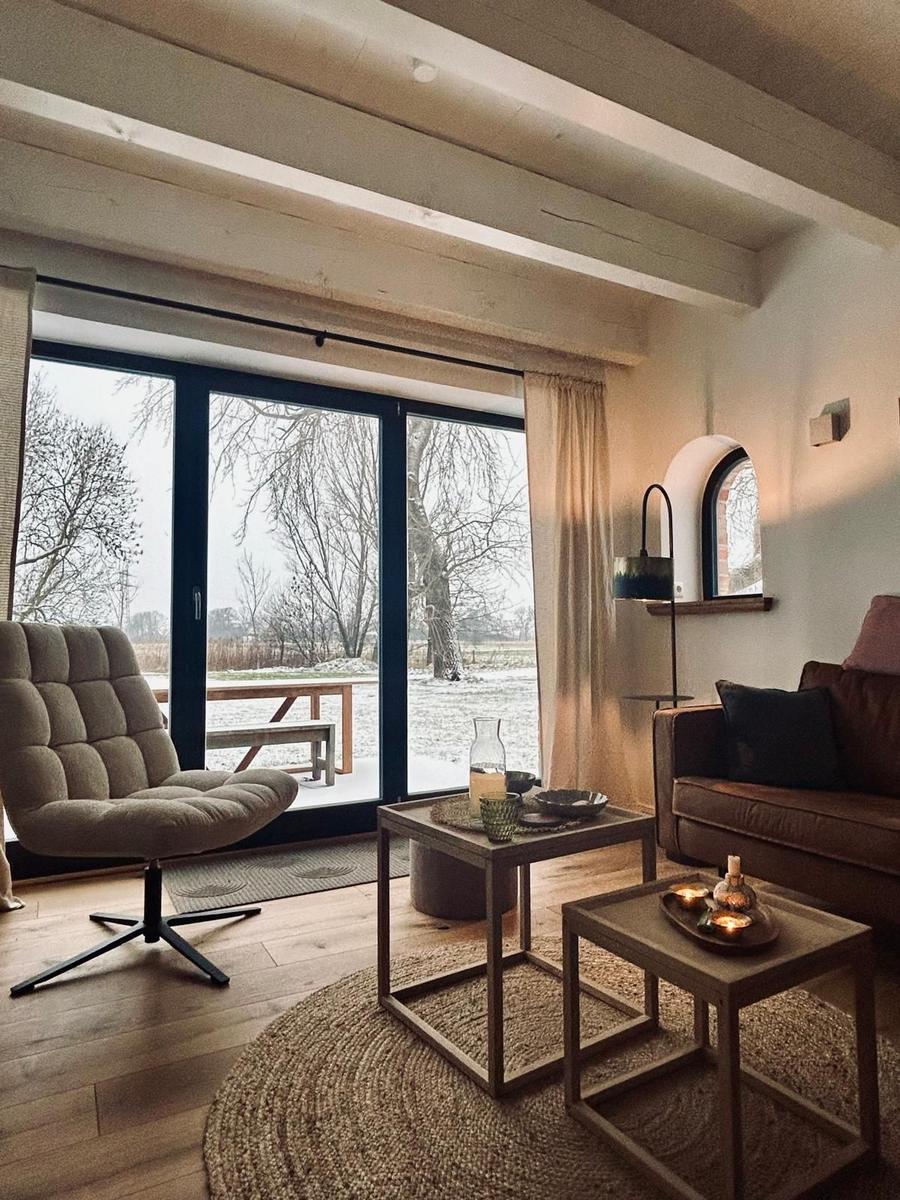 Wohnzimmer mit Sitzgelegenheiten, Tischen und Blick auf schneebedecktes Gelände.