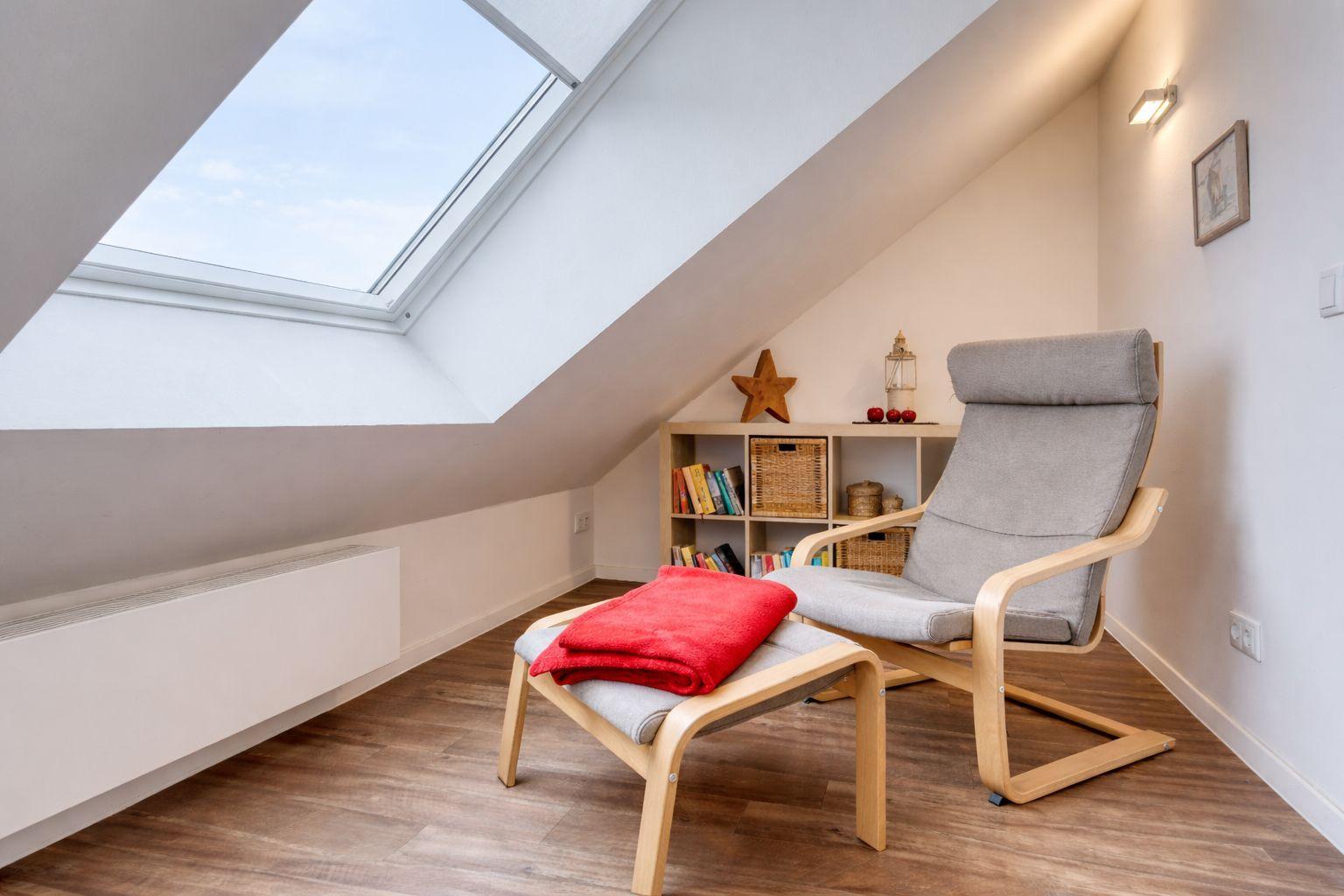 Dachgeschosszimmer mit Sitzgelegenheit und Dachfenster.