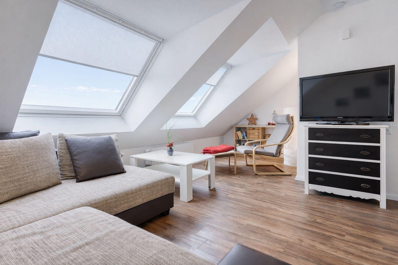 Wohnzimmer mit Dachschrägen, Sofa, Couchtisch und TV.