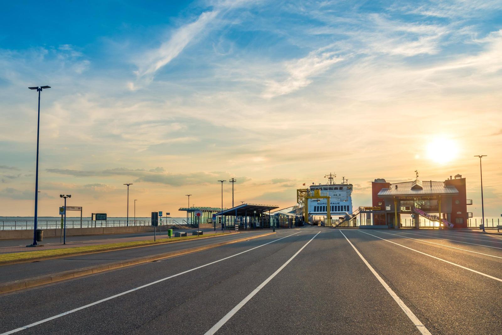 Ferienhafen mit Fähre und Sonnenuntergang am Wasser.