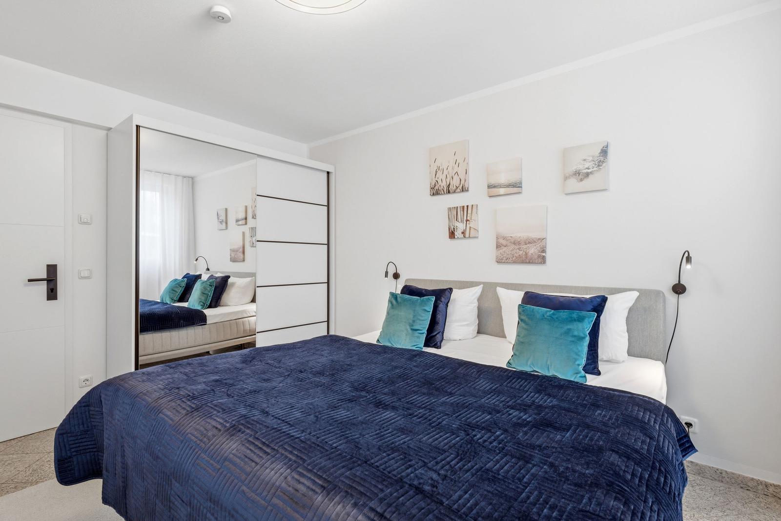 Schlafzimmer mit Bett, Kissen und Wandbildern